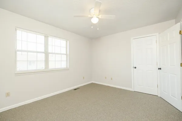 an empty room with a ceiling fan and a window