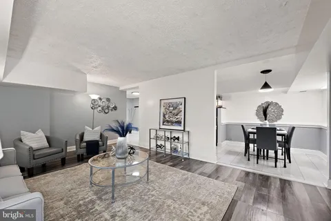 a living room with furniture a dining table and paintings on the wall with wooden floor