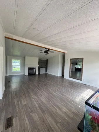 a view of empty room with a fireplace and wooden floor