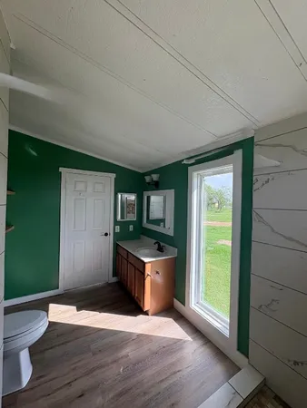 an empty room with wooden floor closet and windows