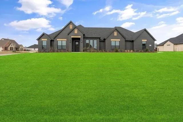 a view of a house with a big yard and large trees