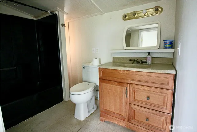a bathroom with a granite countertop toilet sink and mirror