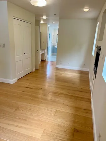 a view of a hallway with wooden floor and a living room