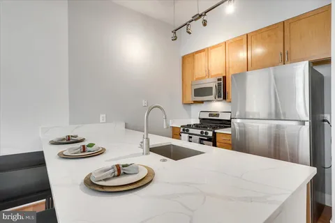 a kitchen with stainless steel appliances kitchen island granite countertop a sink a stove and refrigerator with wooden floor