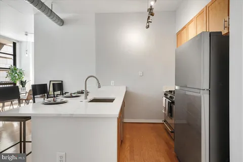 a kitchen with stainless steel appliances kitchen island granite countertop a dining table chairs and a refrigerator