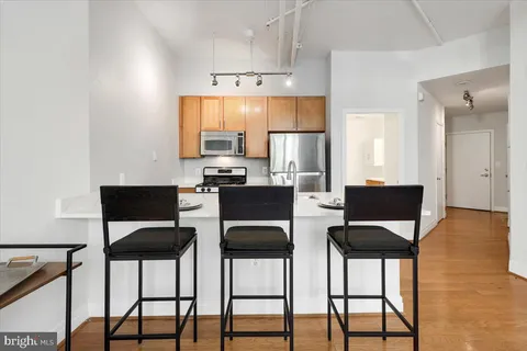 a kitchen with stainless steel appliances kitchen island granite countertop a sink a stove and a wooden floors