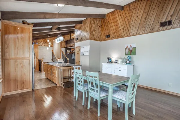 a kitchen with granite countertop a refrigerator a stove a sink and a dining table with wooden floor