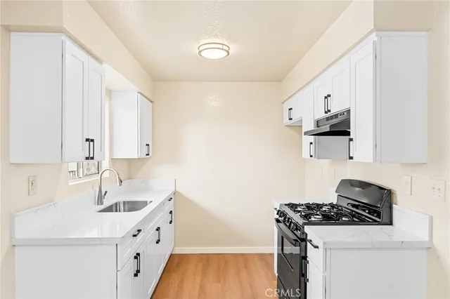 a kitchen with granite countertop a sink stove and cabinets