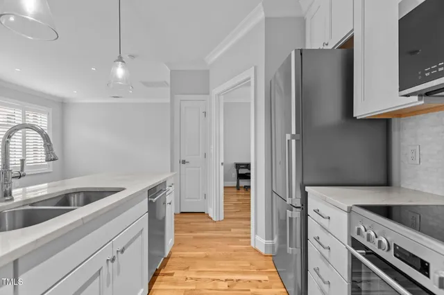 a kitchen that has a sink and a stove with wooden floor