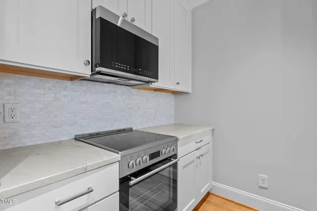 a kitchen with stainless steel appliances granite countertop a sink and a stove top oven with wooden floor