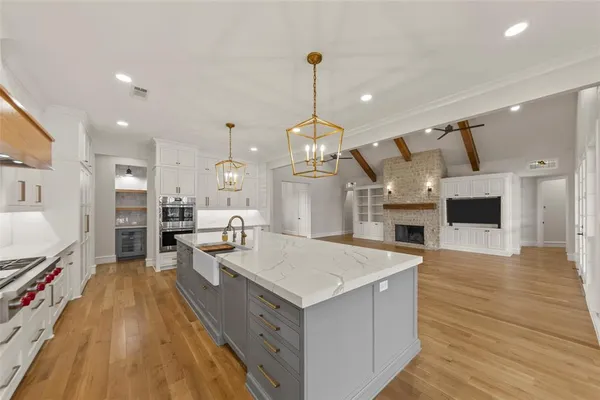 a large kitchen with stainless steel appliances kitchen island granite countertop a stove and a wooden floors