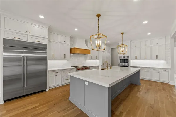 a kitchen with a sink stainless steel appliances a refrigerator and wooden floor