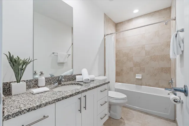 a bathroom with a granite countertop sink a toilet and shower