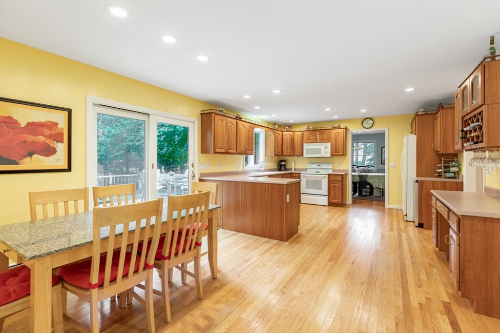 21 Longacre Road Needham, MA 02492 - Photo 17 of 41 a kitchen with stainless steel appliances granite countertop a refrigerator a stove top oven and a dining table with wooden floor
