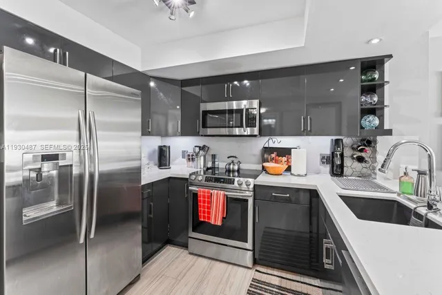 a kitchen with stainless steel appliances granite countertop a refrigerator a stove and a sink with wooden cabinets