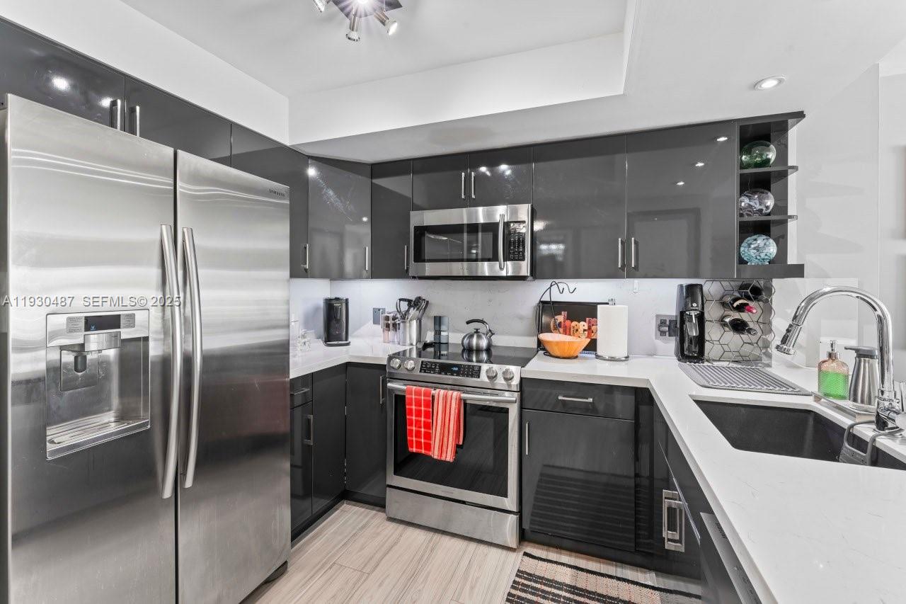1450 Lincoln Road, Unit 307 Miami Beach, FL 33139 - Photo 8 of 18 a kitchen with stainless steel appliances granite countertop a refrigerator a stove and a sink with wooden cabinets