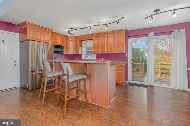 a kitchen with stainless steel appliances a dining table chairs refrigerator and cabinets