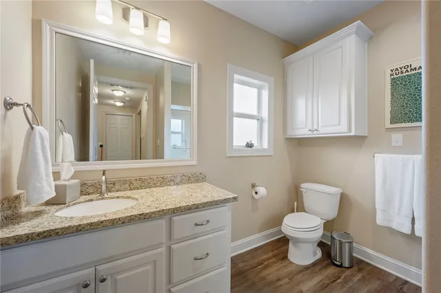 a bathroom with a granite countertop toilet sink and mirror
