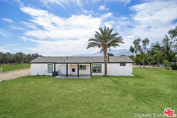 a view of a white house with a large tree next to a yard