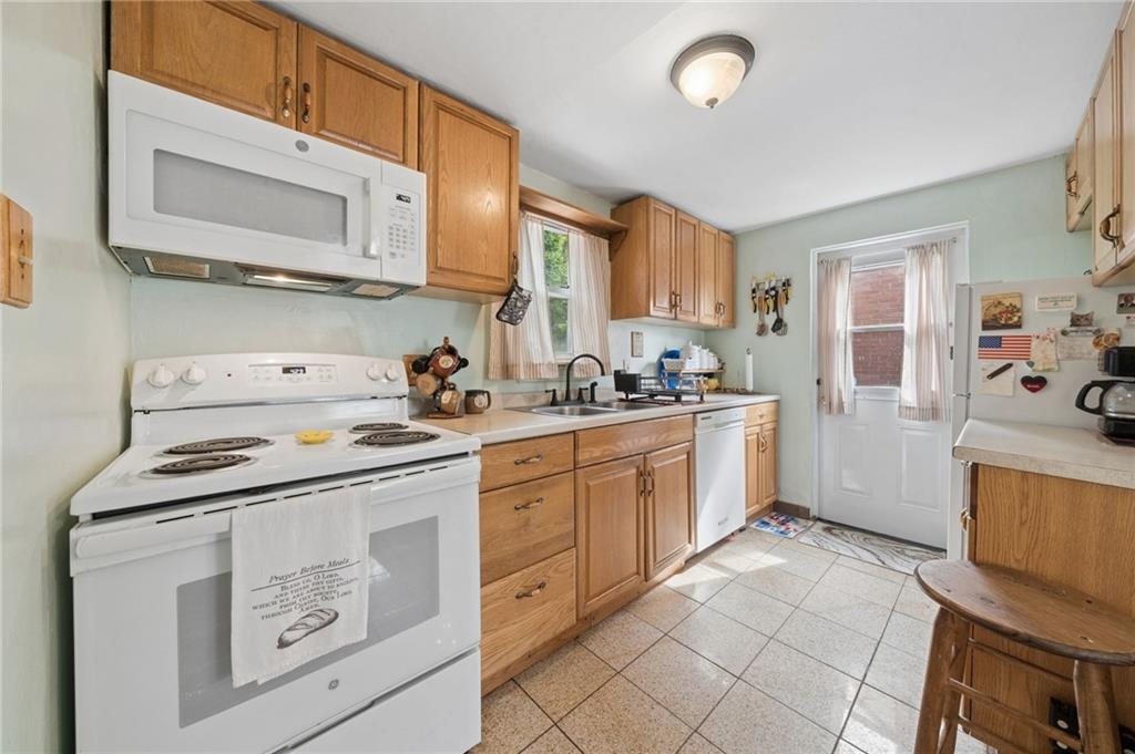 2106 Lindsay Road Pittsburgh, PA 15221 - Photo 7 of 36 This kitchen layout features a modern electric range with a built-in microwave oven mounted directly above the stove to maximize counter space and keep essential appliances within arm's reach.