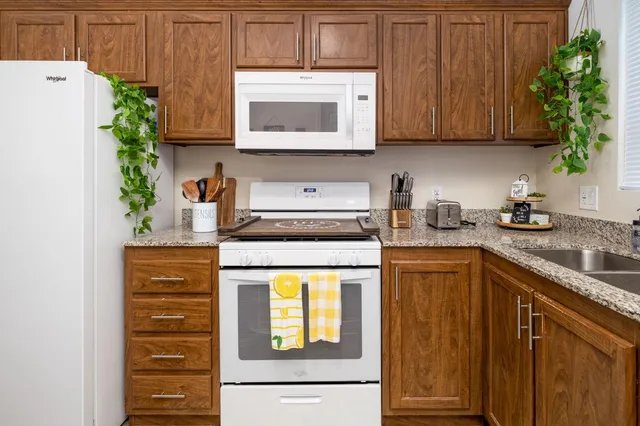 a kitchen with stainless steel appliances granite countertop wooden cabinets and a stove top oven