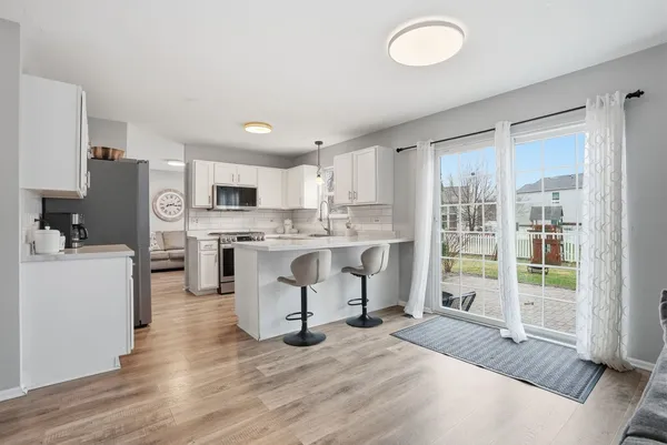 a kitchen with a refrigerator a stove top oven a sink dishwasher and white cabinets with wooden floor