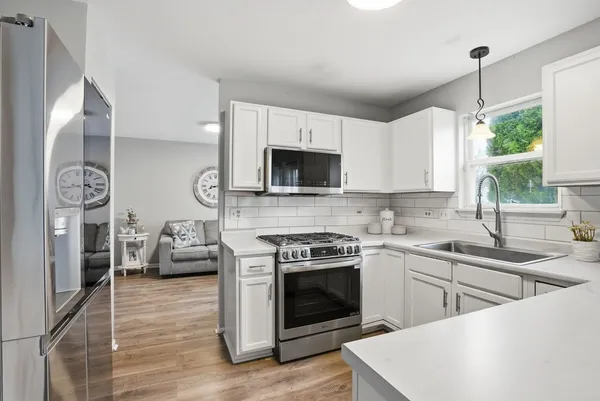 a kitchen with stainless steel appliances granite countertop a stove top oven a sink and a refrigerator