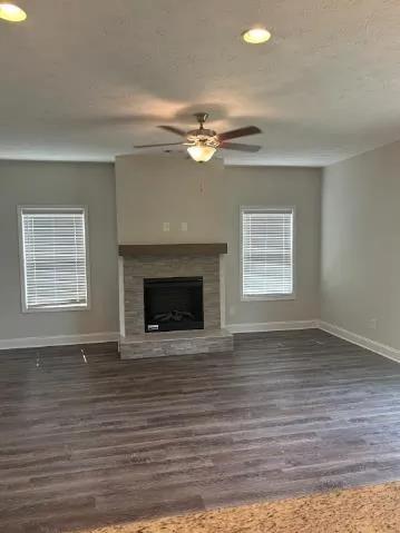 a view of an empty room with wooden floor fireplace and a window