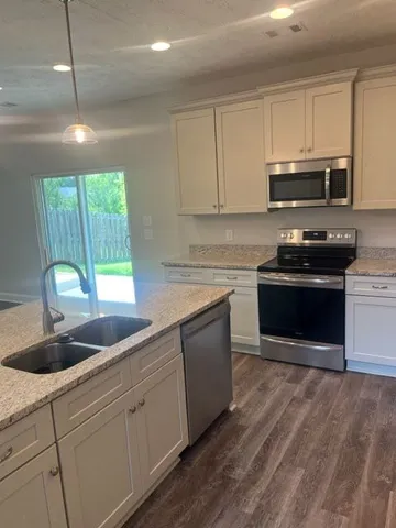 a kitchen with stainless steel appliances granite countertop a stove a sink and a microwave