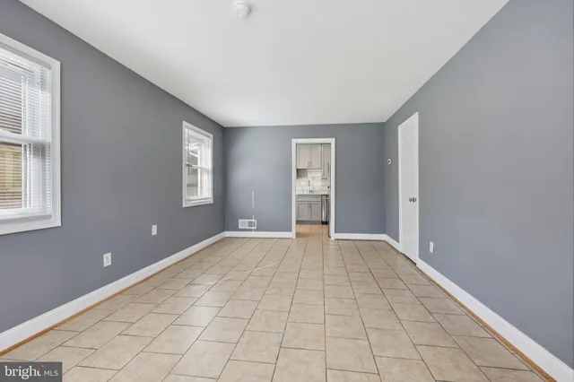 a view of an empty room with window and chandelier fan