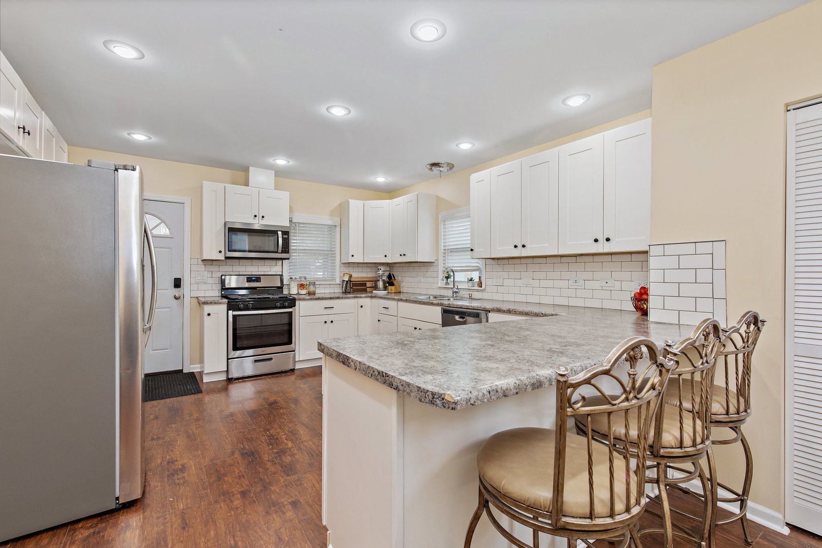 162 Park Street Hampshire, IL 60140 - Photo 3 of 25 a kitchen with stainless steel appliances granite countertop a sink a stove a refrigerator and white cabinets with wooden floor