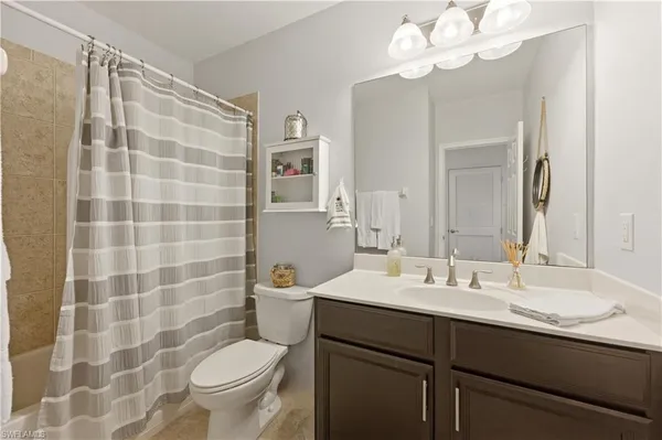a bathroom with a sink a toilet a mirror and shower curtain