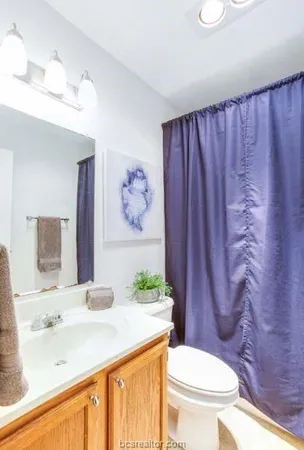 a bathroom with a granite countertop toilet sink and mirror