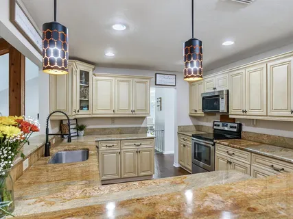 a kitchen with stainless steel appliances kitchen island granite countertop a refrigerator a stove a kitchen island with a dining table and chairs