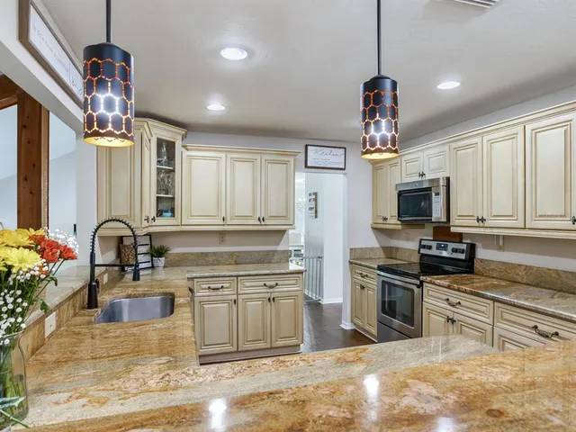a kitchen with stainless steel appliances kitchen island granite countertop a refrigerator a stove a kitchen island with a dining table and chairs