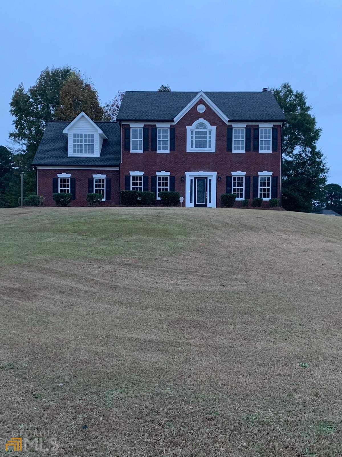 a view of a big house with a big yard and large trees