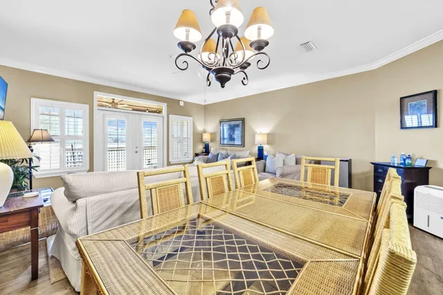 a living room with couches a dining table and a chandelier with wooden floor