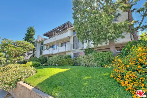 a view of a house with a big yard plants and large trees
