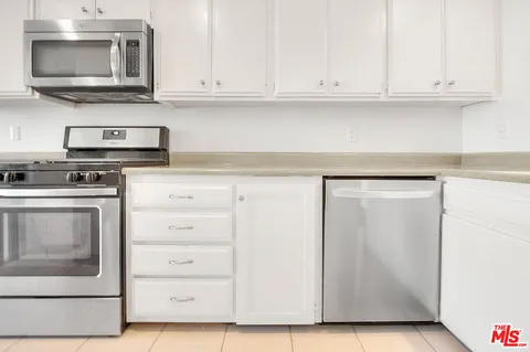 a kitchen with white cabinets and stainless steel appliances