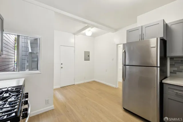 a refrigerator freezer sitting in a kitchen with stainless steel appliances wooden floor and a window