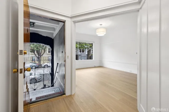 a view of a hallway with wooden floor and a living room