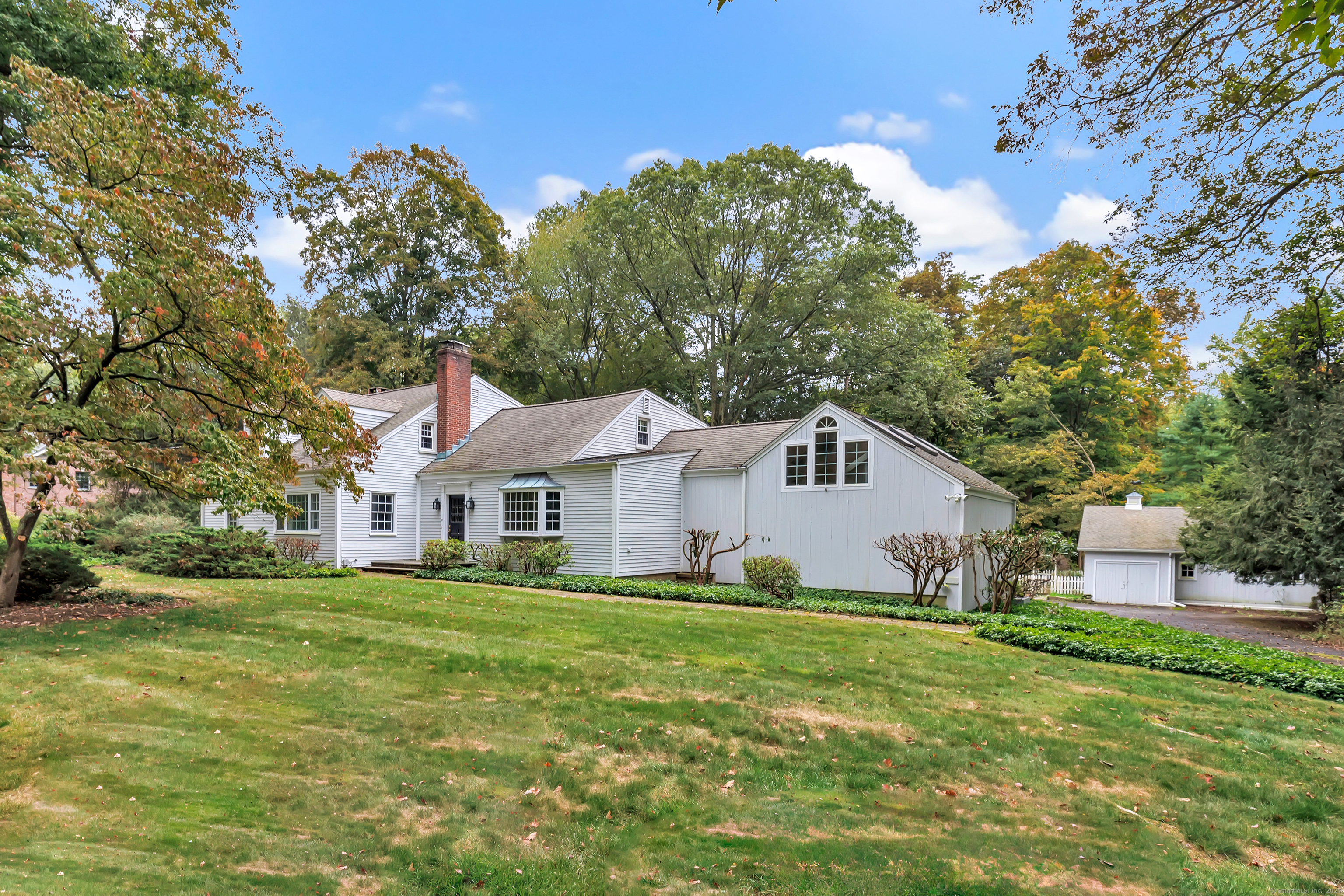 a house that is sitting in the grass with large trees