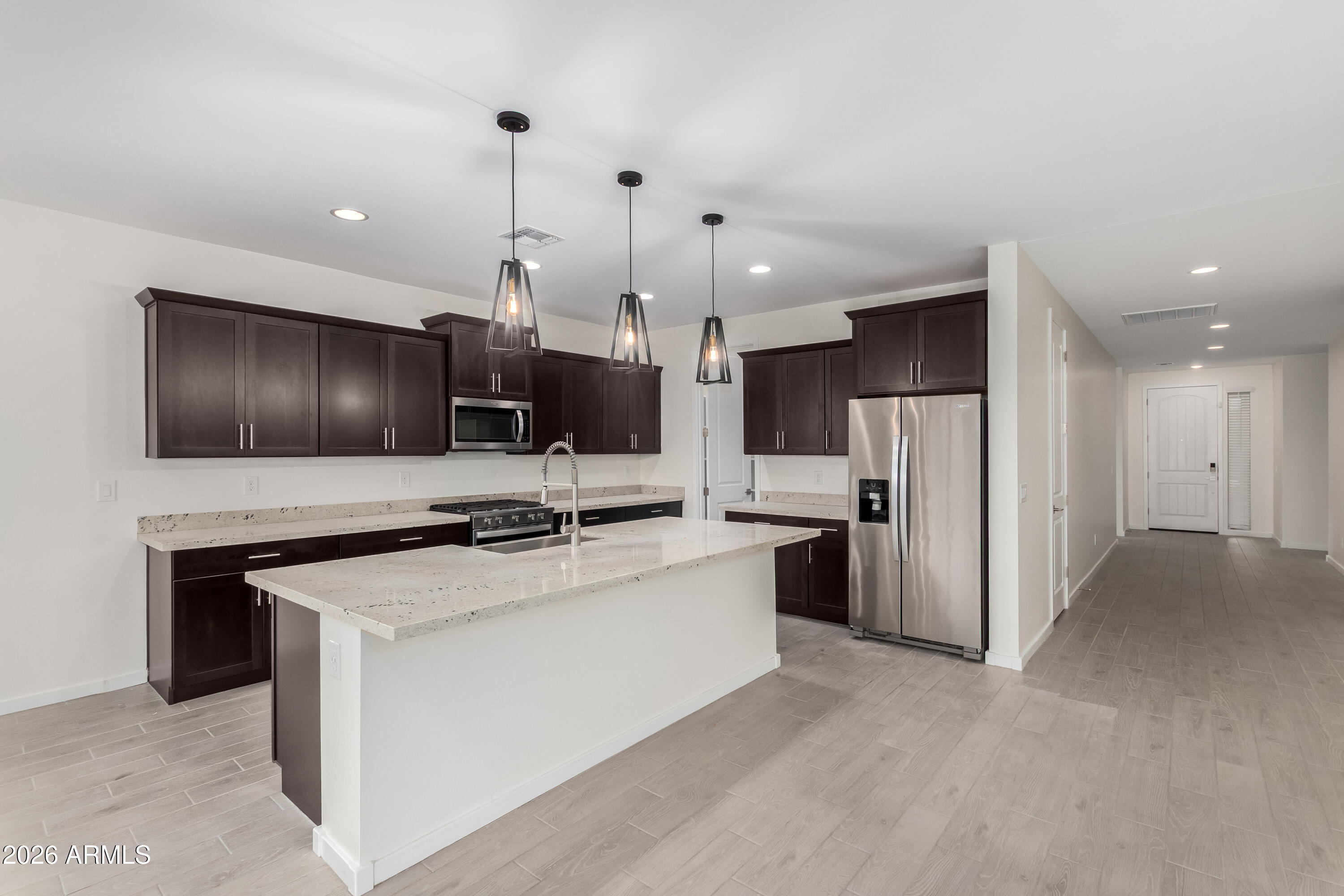 17352 West Red Fox Road Surprise, AZ 85387 - Photo 10 of 45 a kitchen with stainless steel appliances a stove a refrigerator a oven a sink with white cabinets and wooden floor