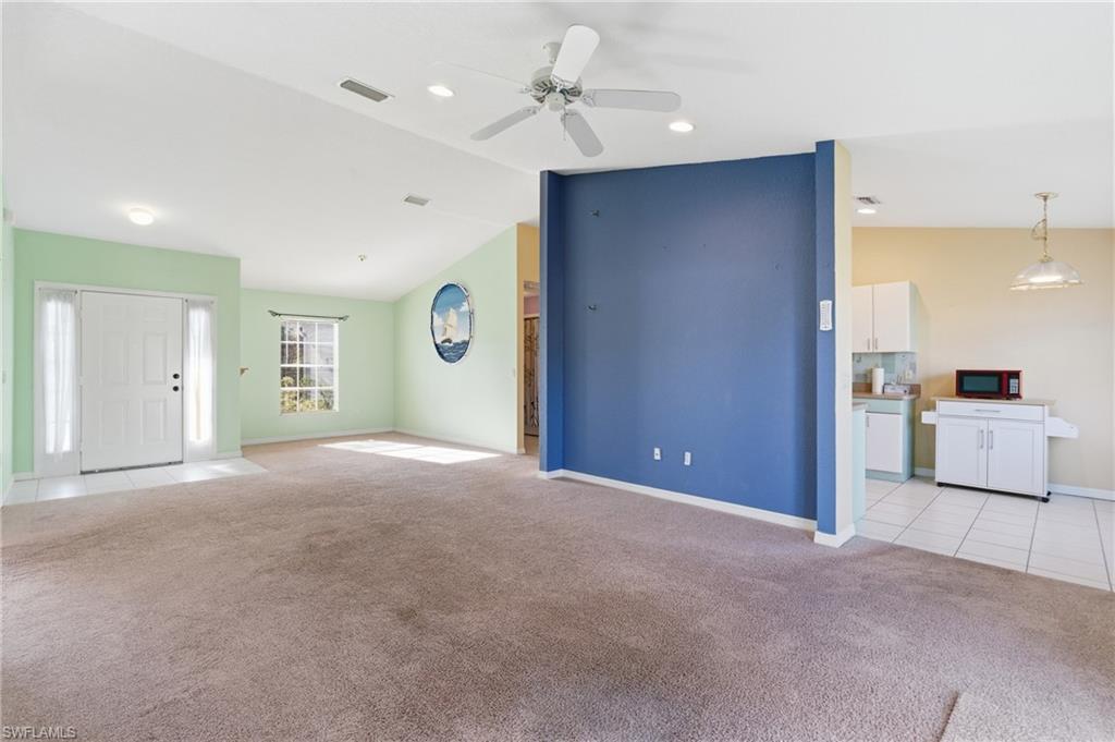1562 Jakway Road North Port, FL 34288 - Photo 15 of 50 Unfurnished living room featuring lofted ceiling, light carpet, a ceiling fan, and light tile patterned floors