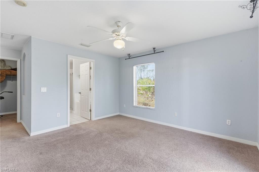 1562 Jakway Road North Port, FL 34288 - Photo 23 of 50 Unfurnished bedroom with light colored carpet, a spacious closet, ceiling fan, and ensuite bath