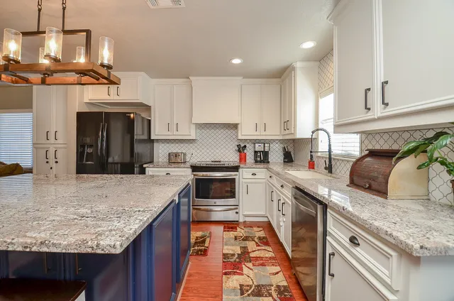 a kitchen with a stove a counter space and living room view