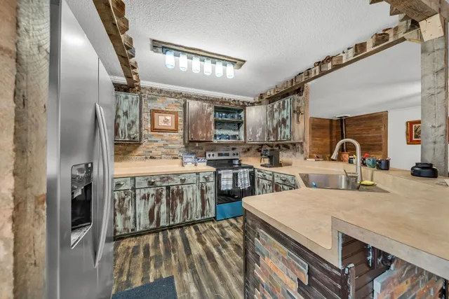 a kitchen with stainless steel appliances granite countertop a refrigerator a stove and a sink with wooden floor
