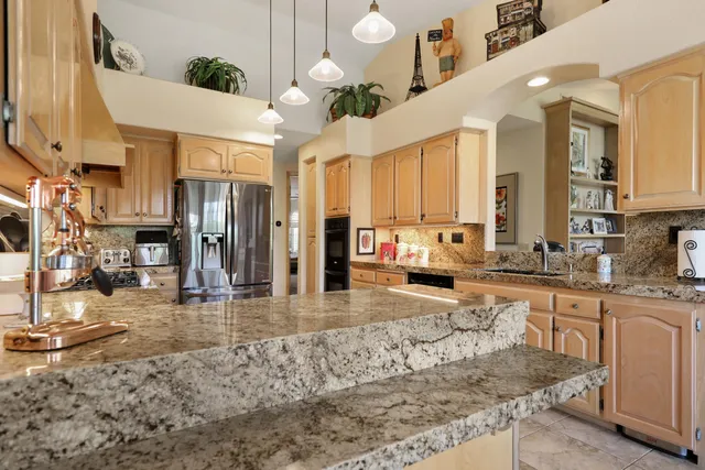 a large kitchen with granite countertop a large window and white stainless steel appliances