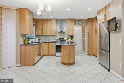 a kitchen with stainless steel appliances granite countertop a refrigerator a sink dishwasher and white cabinets with wooden floor