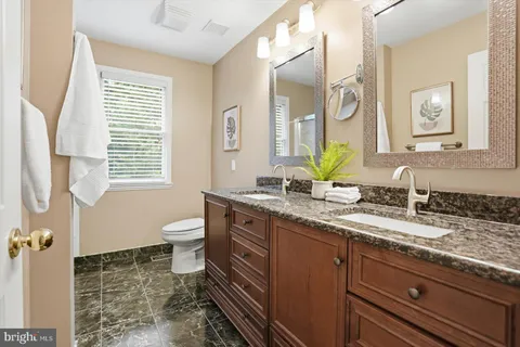 a bathroom with a granite countertop toilet a sink and a mirror
